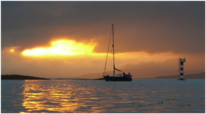 Leuchturm und Segelschiff w�hrend des Sonnenuntergangs im Firth of Lorn, fotografiert von der Strandpromenade in Oban. (09.08.2008)